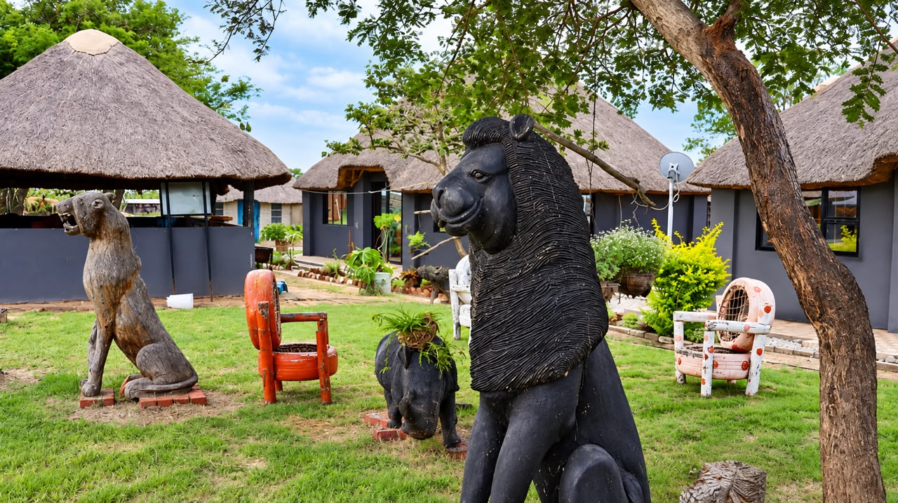Carved lion and elephant statues in the Shayanewako garden, set among the thatched-roof compound